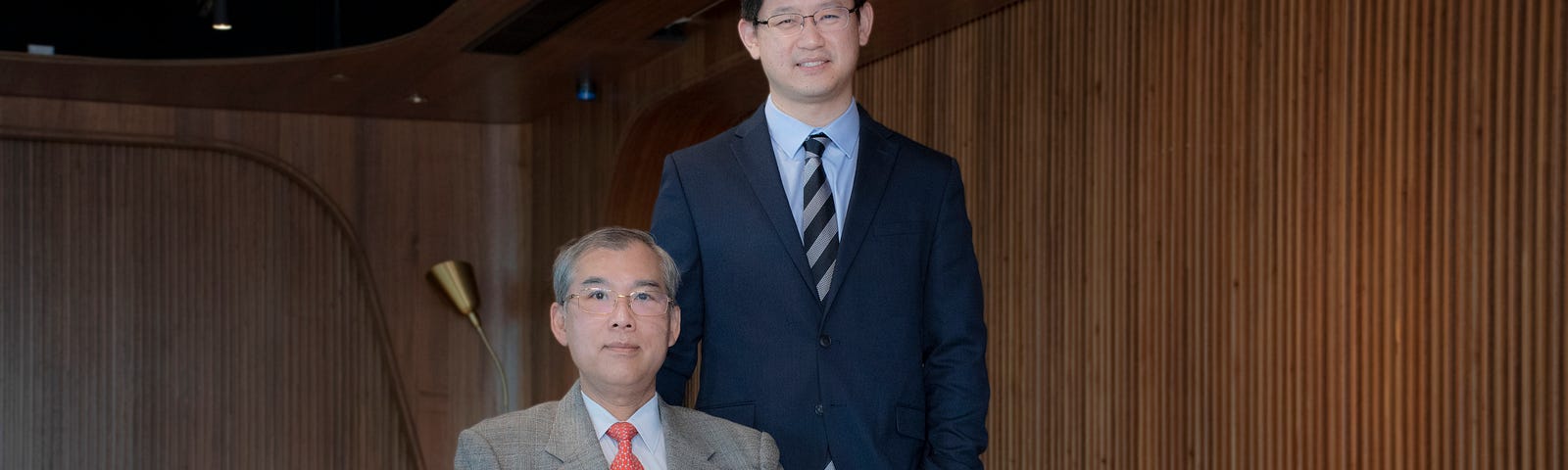 Professor Keith Luk sits in a chair in front of his menteee Dr Jason Cheung