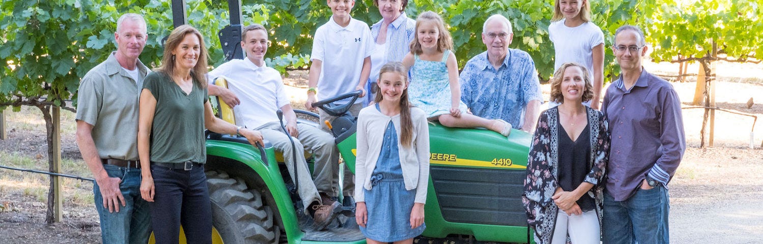 Family standing around tractor at a vineyard