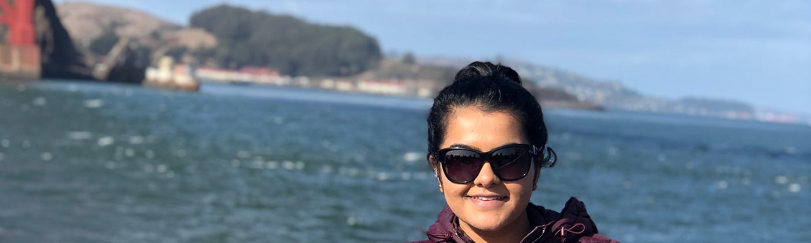 Juhi standing on the deck of a boat under the Golden Gate bridge.