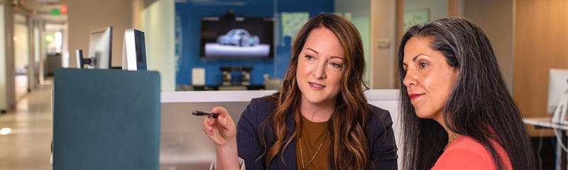 A product manager and designer collaborating together in front of a computer
