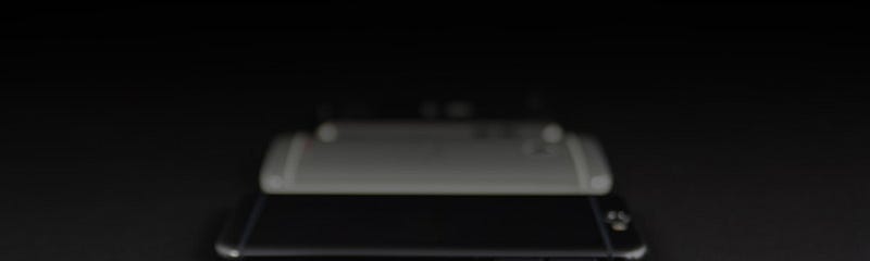Three gray or black phones lined up face down