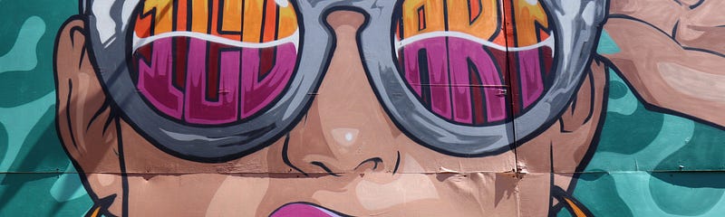 Person holding the side of sunglasses showing off a colored tooth in a cocky and cool sort of pose.