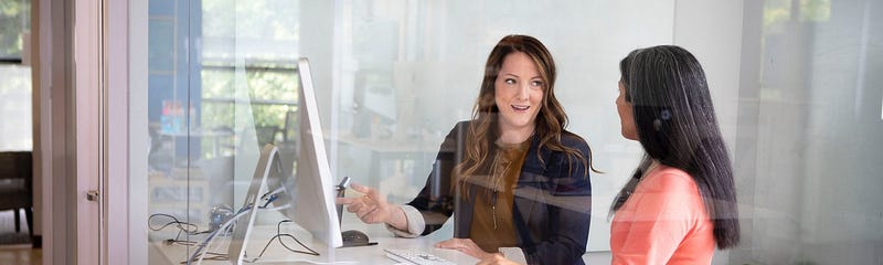 Two women at standing desk working