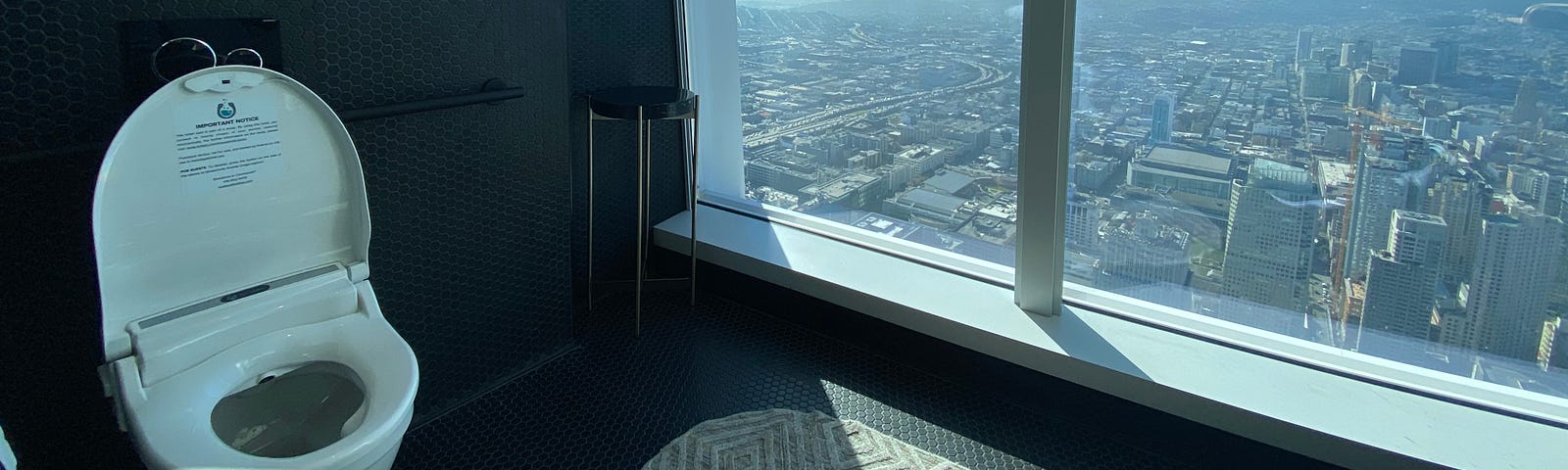 A photo of a smart toilet in a bathroom within a high-rise building overlooking the city.