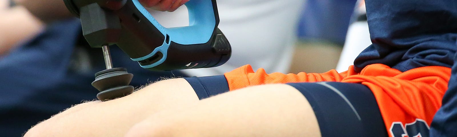 A Syracuse Orange player uses a TheraGun during warm ups prior to the game against the Connecticut Huskies.