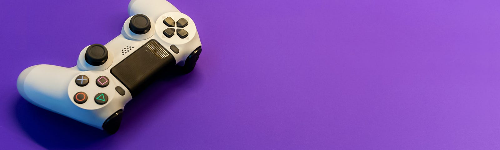 a white gaming controller on a purple background