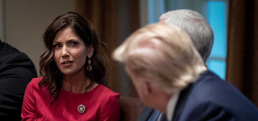 A photo of Kristi Noem talking to Mike Pence and Donald Trump at a meeting.