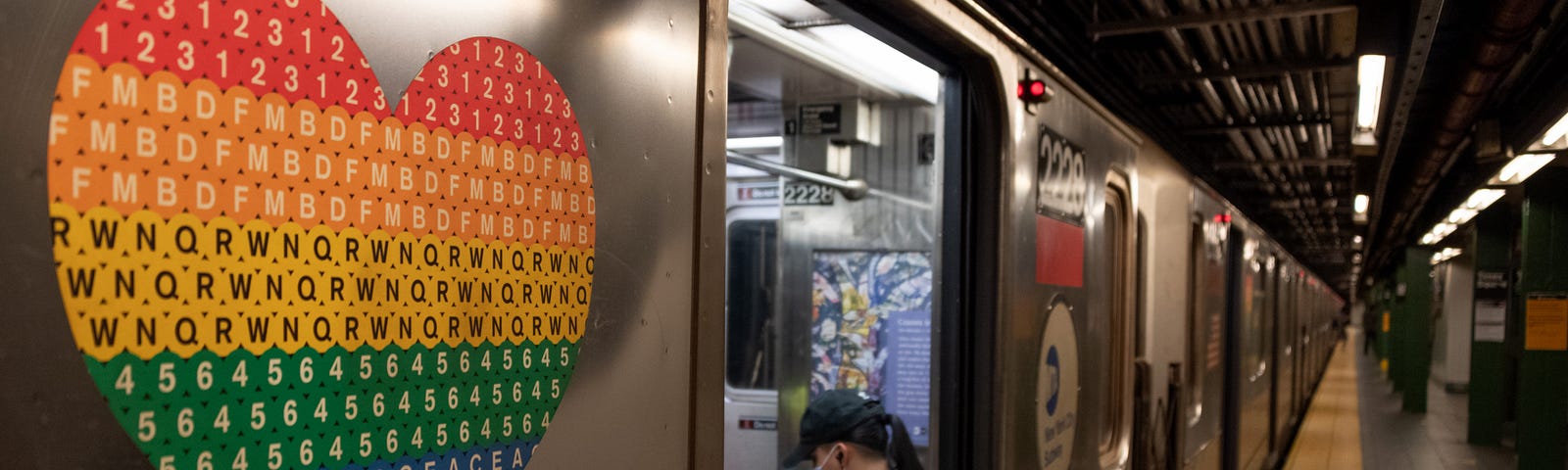 A pride colored heart is seen on a subway car near a person wearing a mask as the city moves into Phase 2 of re-opening following restrictions imposed to curb the coronavirus pandemic on June 25, 2020 in New York City.