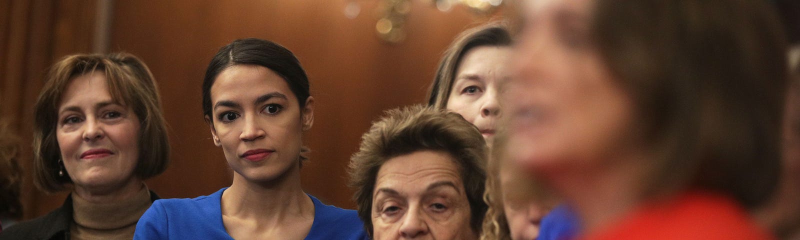 U.S. Reps Alexandria Ocasio-Cortez, Kathy Castor, and Donna Shalala listen as  Speaker of the House Nancy Pelosi speaks.