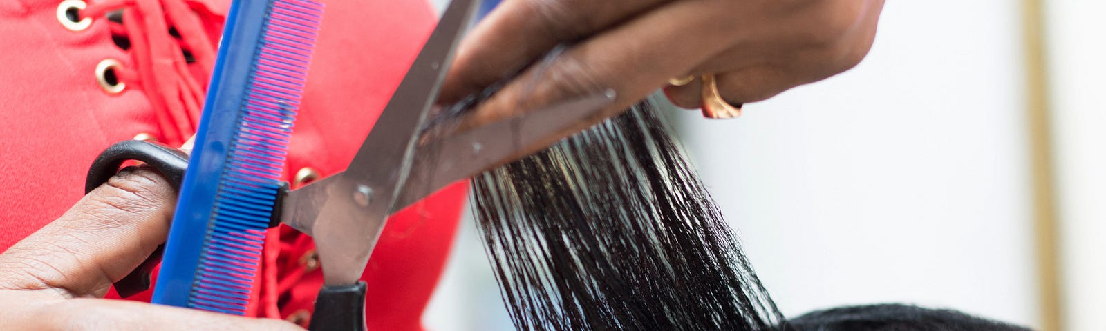 A closeup photo of a hair stylist cutting a client’s hair.