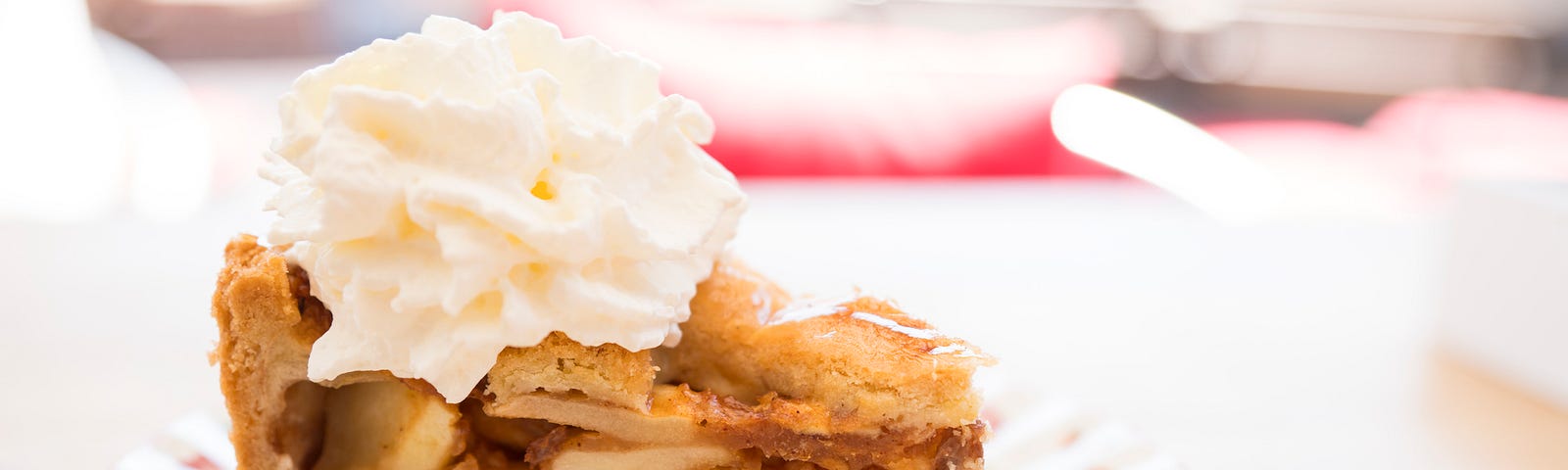 A picture of a slice of apple pie with whipped cream.