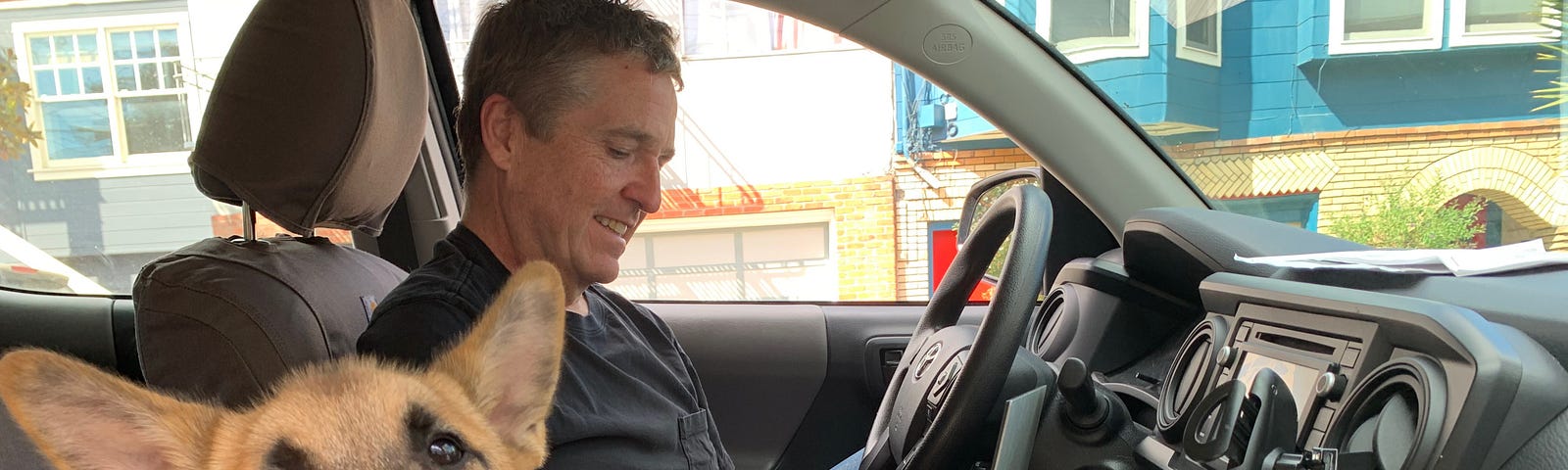 American Giant CEO Bayard Winthrop working on his laptop out of his truck with his 3-month-old puppy.