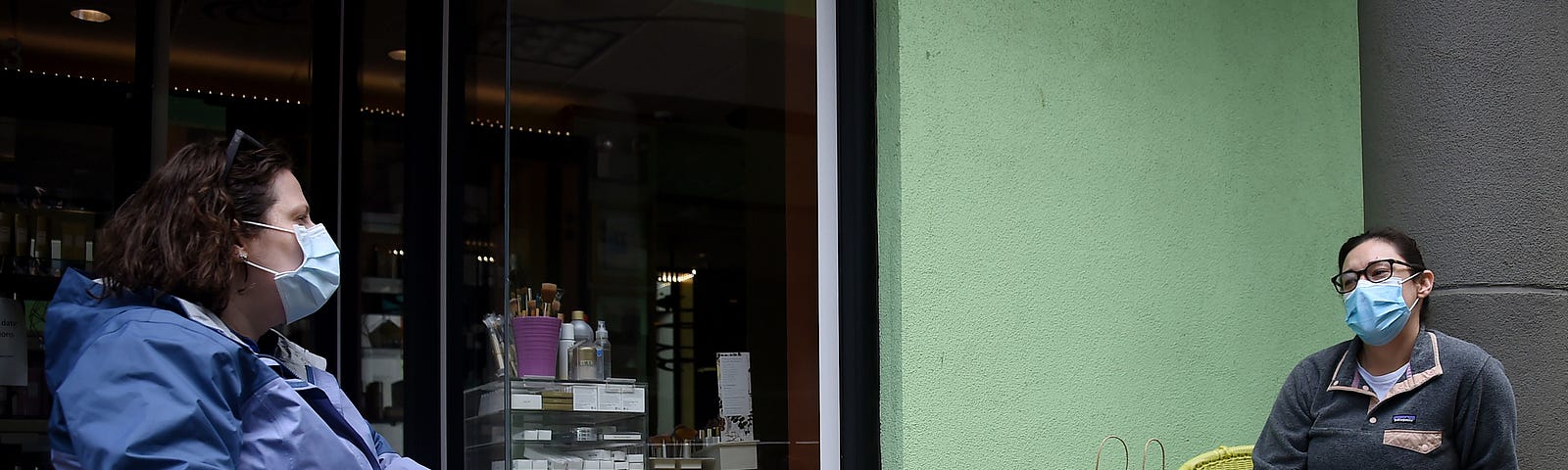 Friends wearing face masks practice social distancing as they chat in front of a shop during the outbreak of COVID-19.