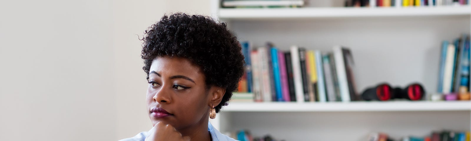 An African American businesswoman looking pensive while at home, in front of her laptop.