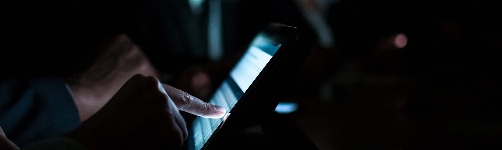 Dark photo of tech workers on tablets.