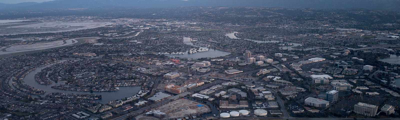 Aerial view of Silicon Valley at dusk, with a portion of the San Mateo/Hayward Bridge visible, as well as Foster City, including the California headquarters of Gilead Sciences, Visa, and Conversica, California, July, 2016.