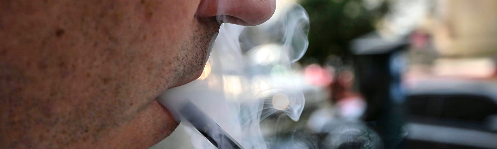 A closeup photo of a man exhaling smoke from an electronic cigarette in Washington, DC on September 12, 2019.