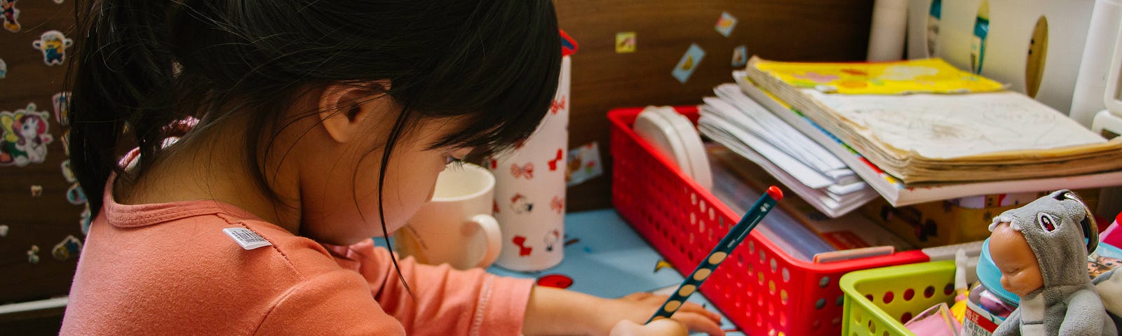 A young Asian girl is doing her homework at her desk.