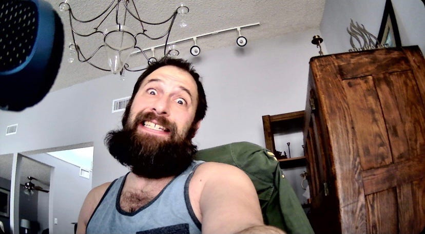 Photograph of Hogan Torah sporting a voluminous beard in an office setting.