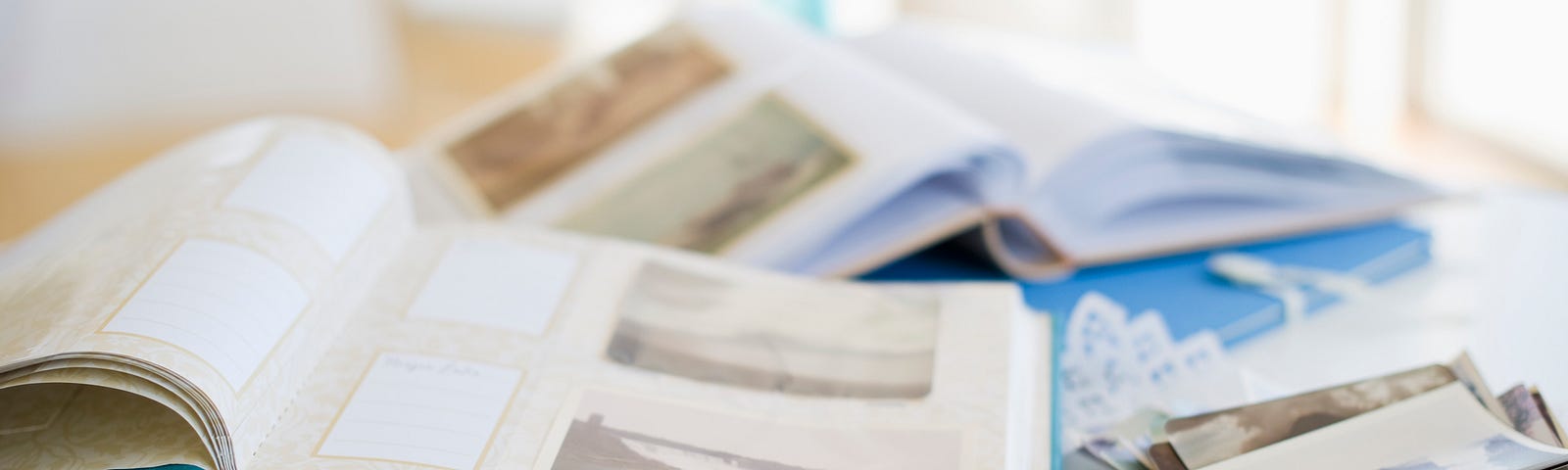 A photo of two photo scrapbooks on a table with some polaroids on the side.