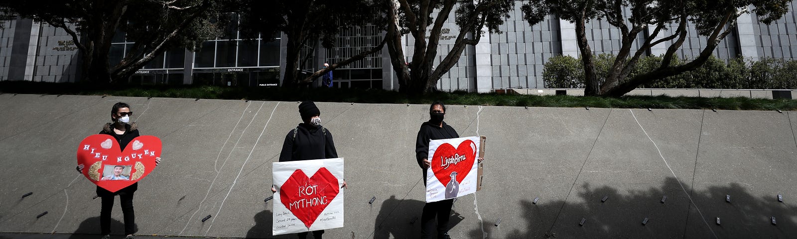 Activists hold signs and tombstone shapes in front of the Phillip Burton Federal Building to honor Covid-19 victims.