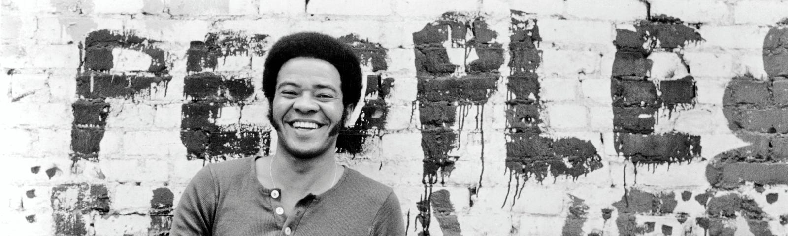 Bill Withers poses for a portrait against a brick wall circa 1973.