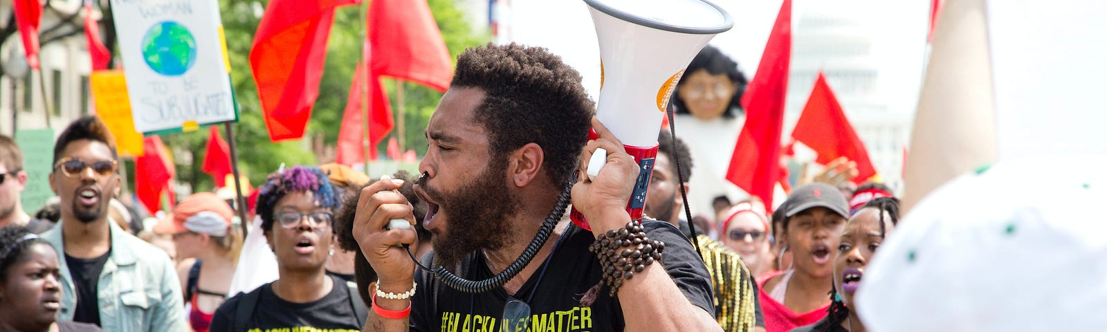 A photo of a protestor speaking into a megaphone at a protest for BLM.