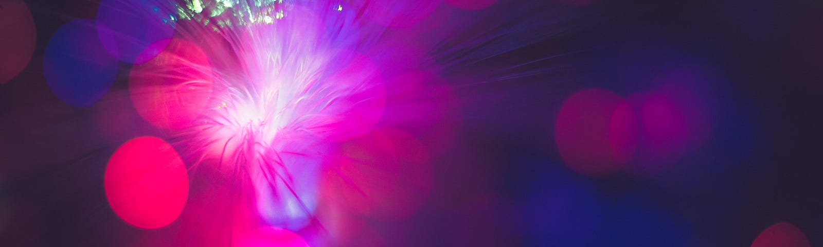 An abstract image of red, violet, and green light flares and a starburst.