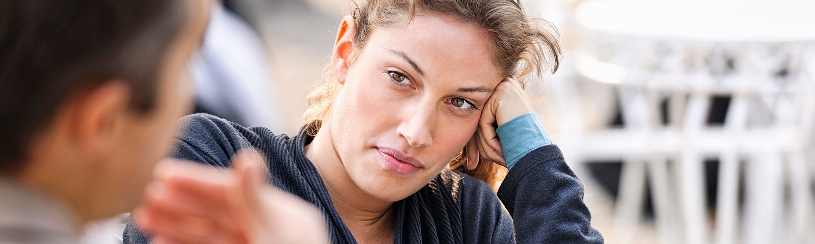 A photo of a slightly disgruntled woman looking at a man talk, waiting for him to finish.