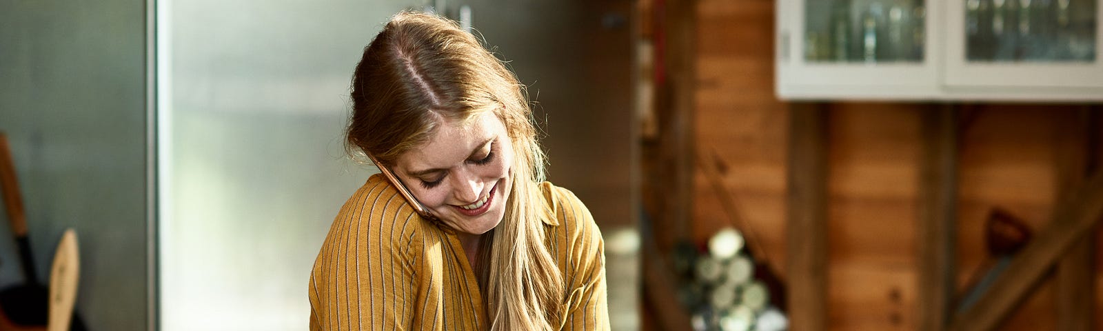 Young woman multitasking talking on the phone while washing dishes.