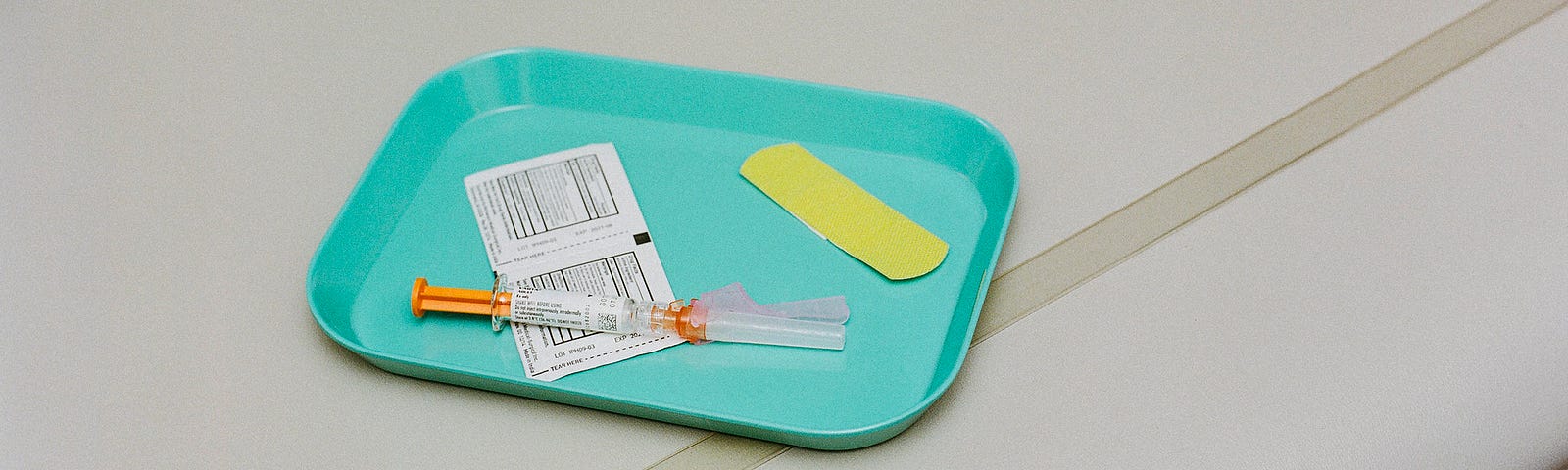 A tray with a bandaid and shot.