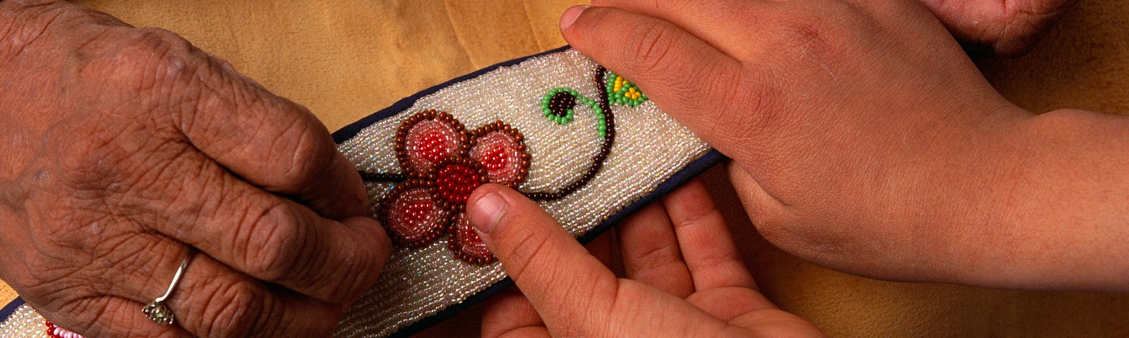 A photo of an elderly Ojibwe showing an embroidery to a young child.