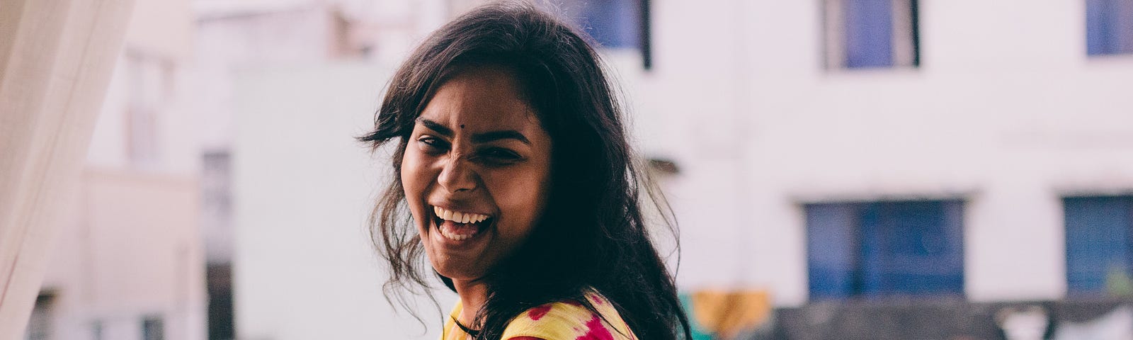 Joyful dark-skinned South Asian woman outside looking at the camera.