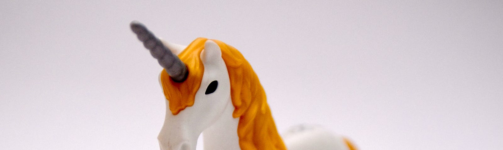 a white unicorn toy with orange hair