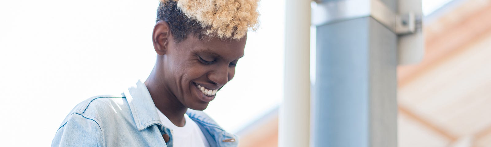 A side view of a non-binary African American person using their smartphone.