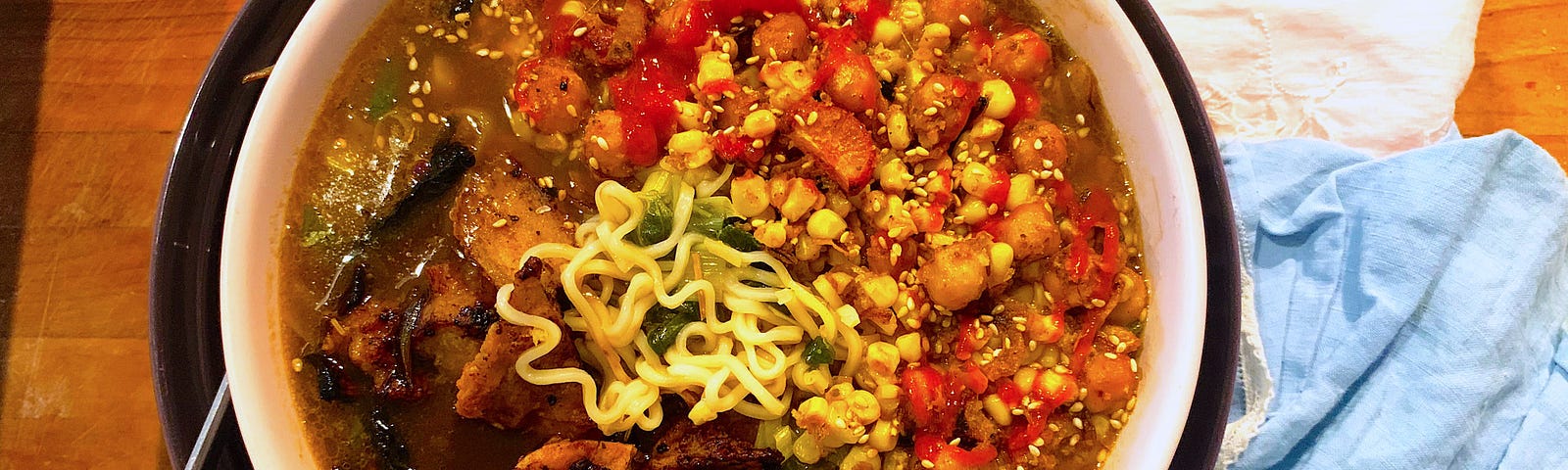 vegetable ramen noodle bowl with chickpeas, blackened mushrooms, and noodles peeking out from the broth