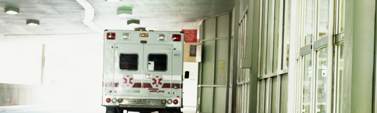 A photo of an ambulance in front of a hospital entrance.