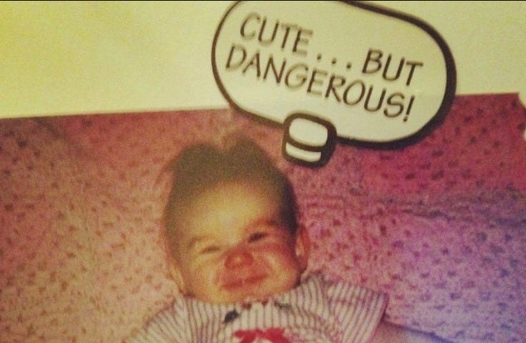 A photo taken of Ashley as a baby, smiling, with a sticker that says “Cute… but dangerous!” #babypicture #scrapbook