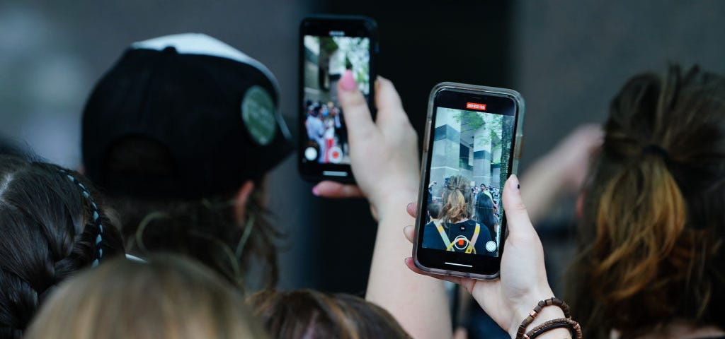 A photo of protestors recording videos on their phones.