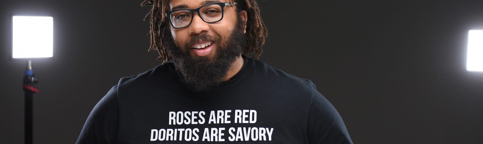 Kurt Evans in front of a black backround and studio lights, wearing a shirt saying the US prison system is legalized slavery.