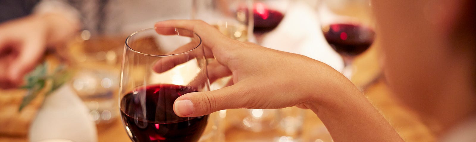 Woman holding a wine glass filled with red wine.