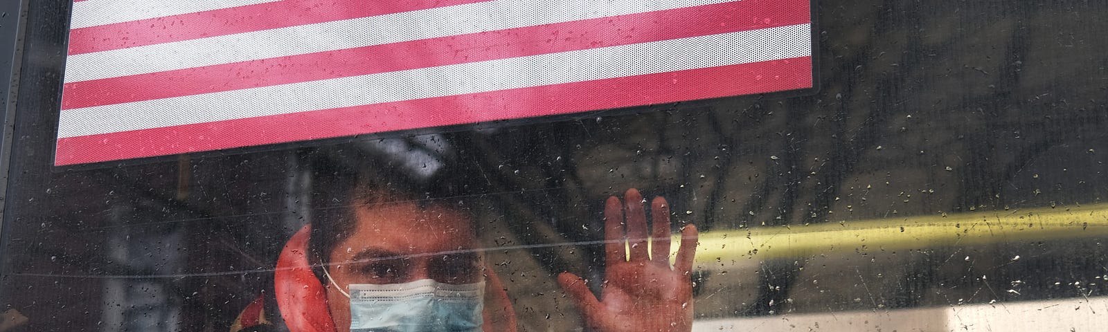 A man waves from a bus in a neighborhood in the Queens borough, which has one of the highest infection rates of coronavirus.