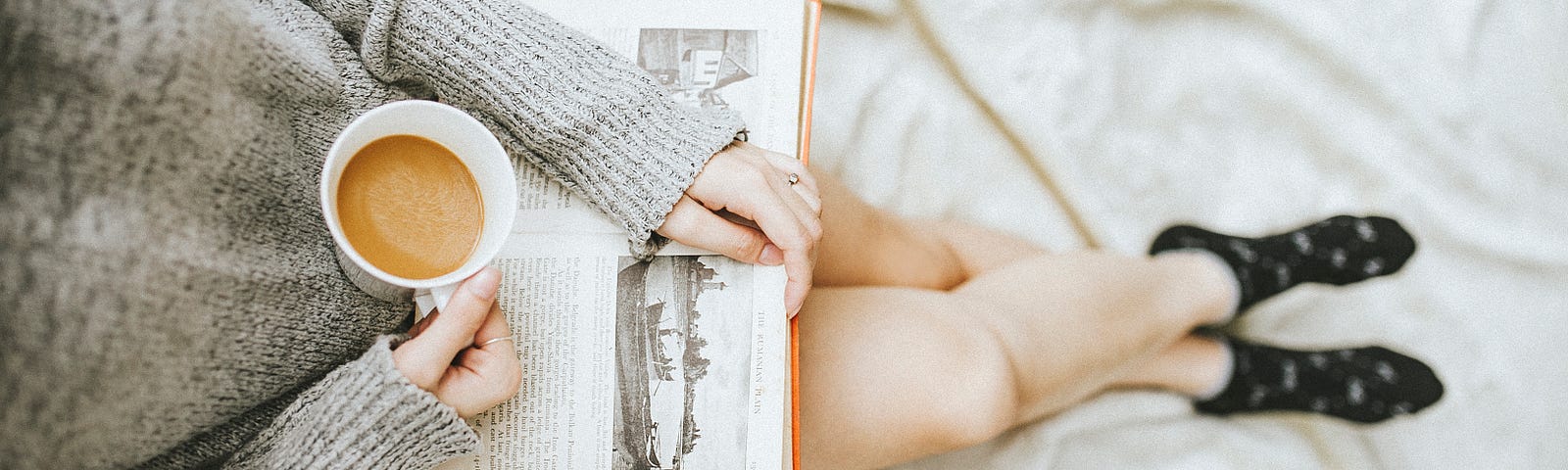 girl holding a coffee mug reading a book