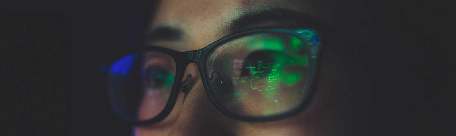 Reflection on glasses of woman working late at night on computer.