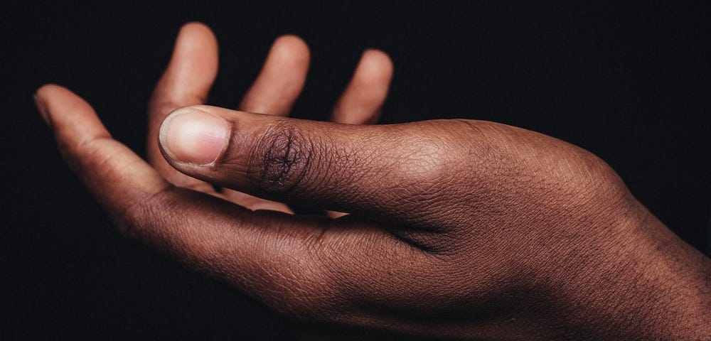 Black woman’s empty palm against a black background.