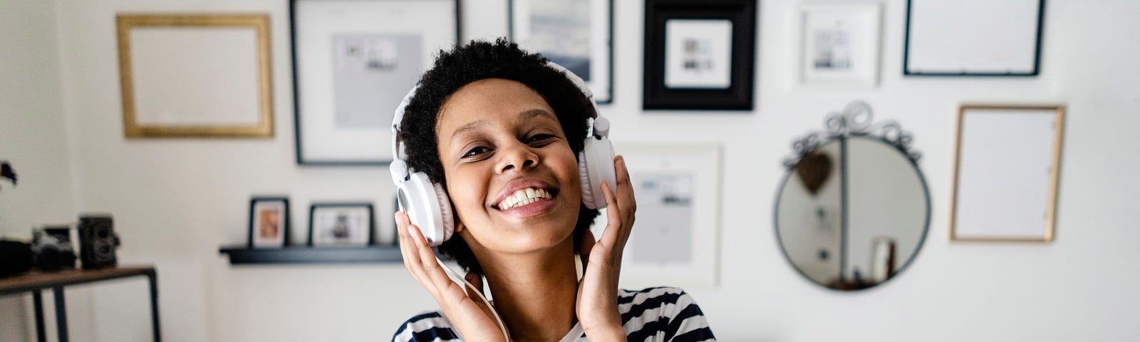 Black woman listening to music on headphones at home.