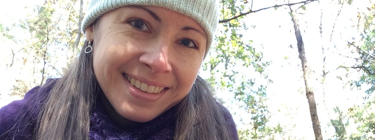 Woman smiling and holding a marbled salamander to the camera. Salamander is black with white markings.