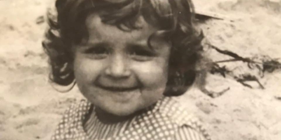 A black and white photo of the author as a two-year-old sitting in the sandbox.