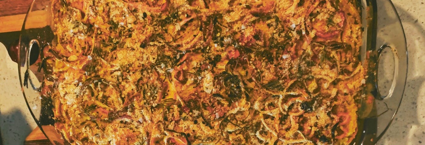 Overhead shot of a casserole topped with crispy bits in a clear casserole dish on a wooden cutting board.