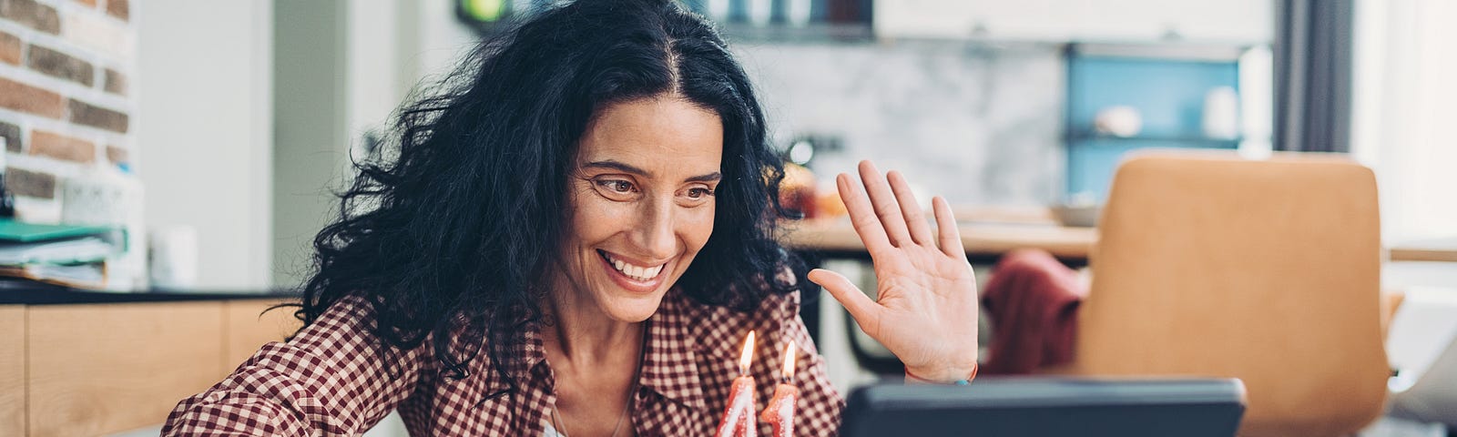 Woman waving hi during a video call.